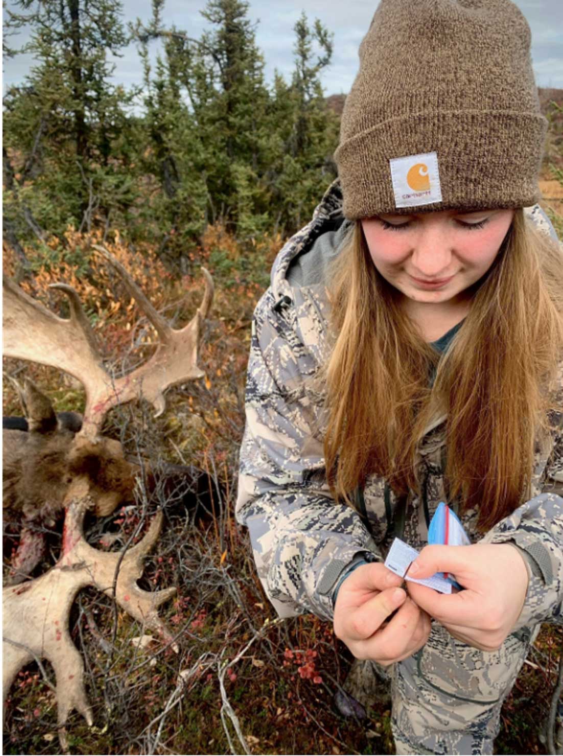 Female hunter notching game tag with antlers in the background