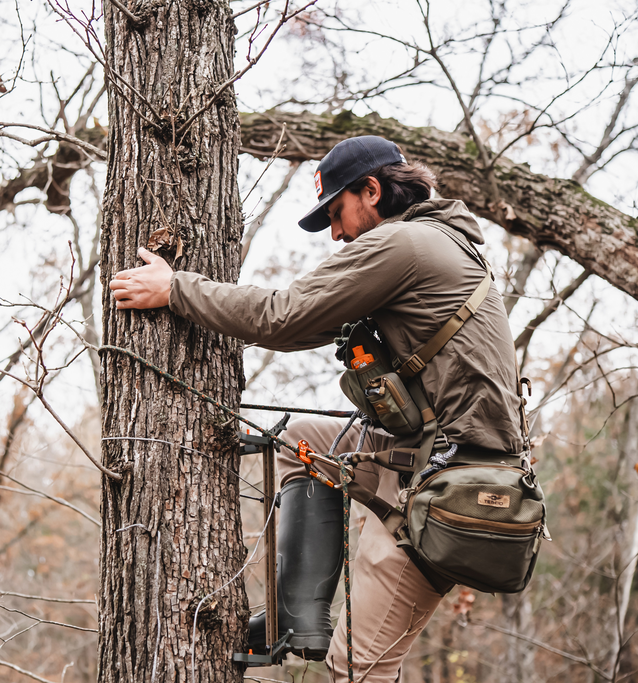 Hunter climbing a tree with a climbing stick